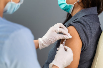 Nurse administering injection to patient's left arm