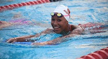Young person with cap and goggles swimming in a pool