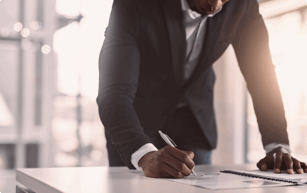 Athlete in black suit leaned over desk signing documents