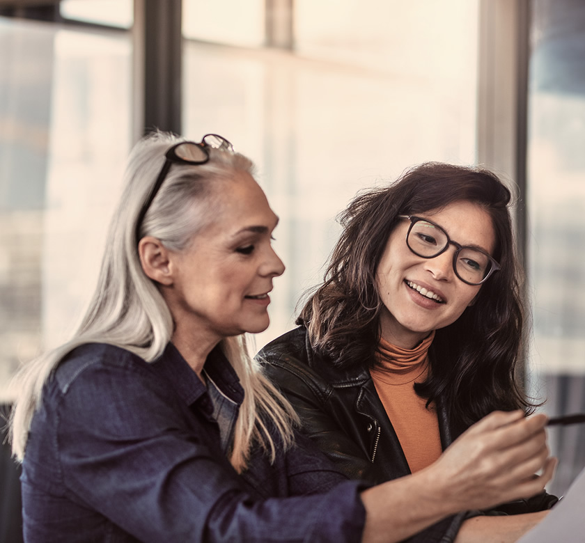 Two women analyzing documents at office