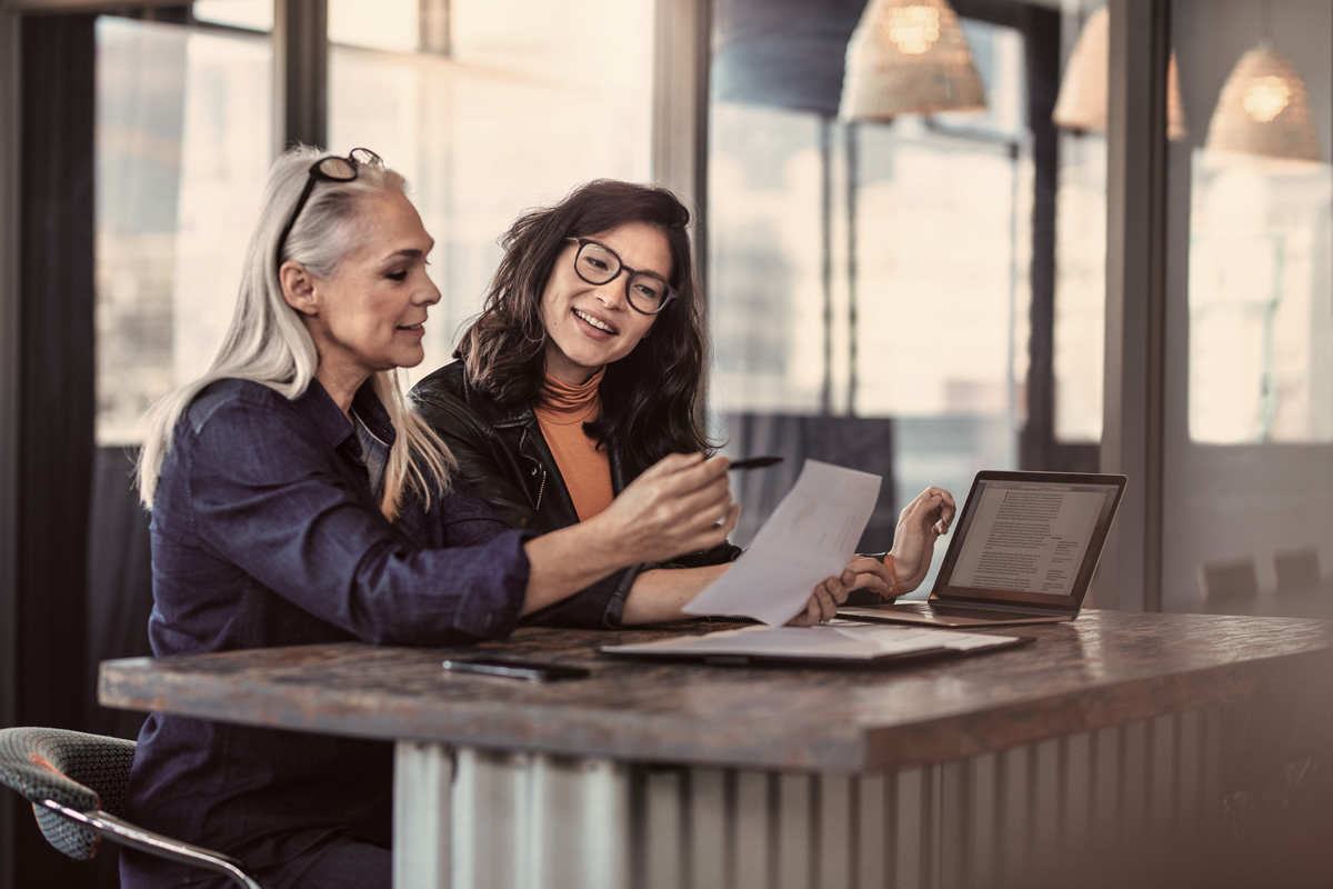 Two women analyzing documents at office