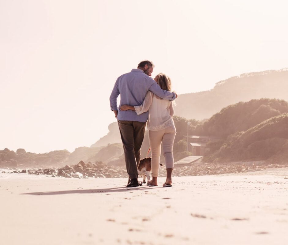 Romantic couple walking along the beach with a dog