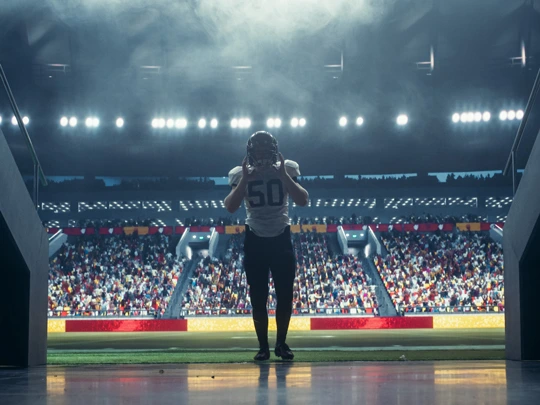 A professional football player walking off the field towards the viewer. - For Athletes