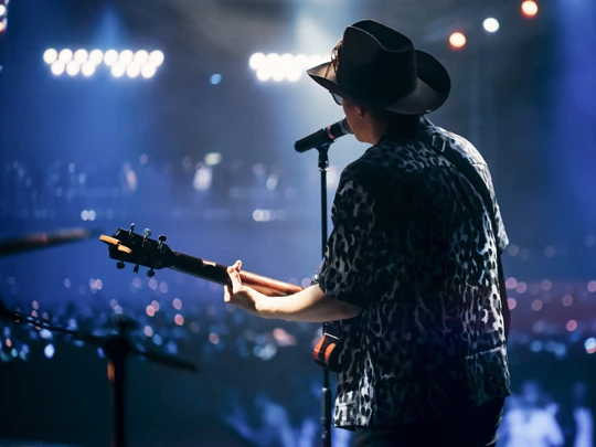 Musician performing on stage in front of full house - For Emerging Creators